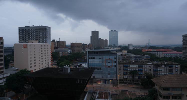 Skyline de la ciudad de aspecto sombrío con edificios de gran altura bajo nubes de tormenta oscuras al atardecer