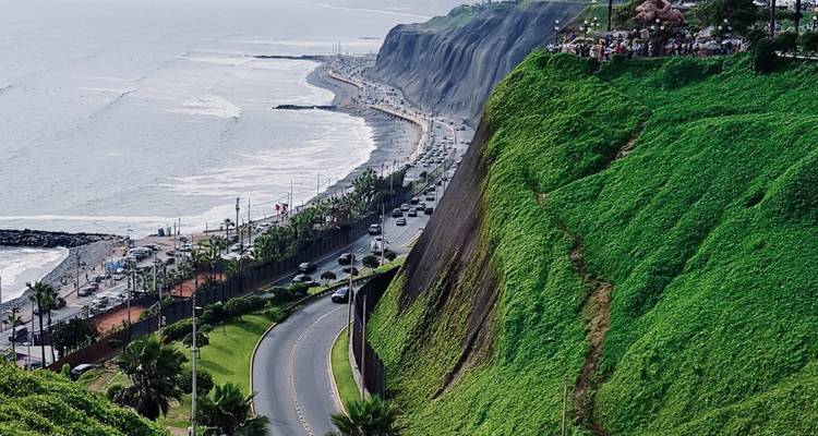 Impressionnante falaise verdoyante surplombant l'autoroute côtière et les vagues du Pacifique dans un paysage urbain
