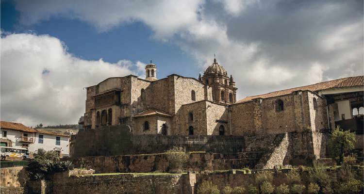 Complexe d'église coloniale en pierre et de couvent situé sous un ciel chargé dans les Andes.