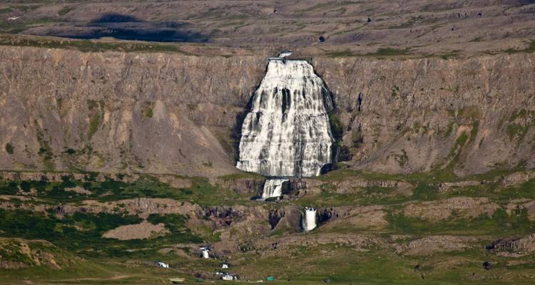Vue lointaine de la majestueuse cascade de Dynjandi se déversant sur des falaises en terrasses dans une vallée de fjord isolée.