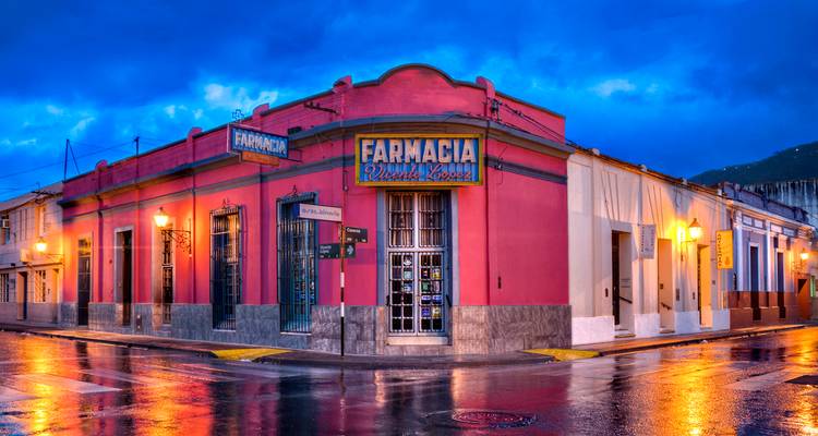 Un edificio de farmacia en una colorida esquina refleja las luces de la ciudad en las calles mojadas después de la lluvia.