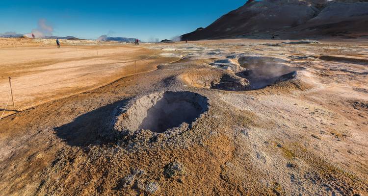 Steaming geothermal craters and fumaroles on a barren, colorful volcanic plain