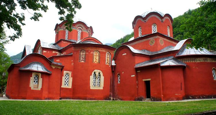 Striking red-painted Patriarchate of Peja monastery complex surrounded by greenery