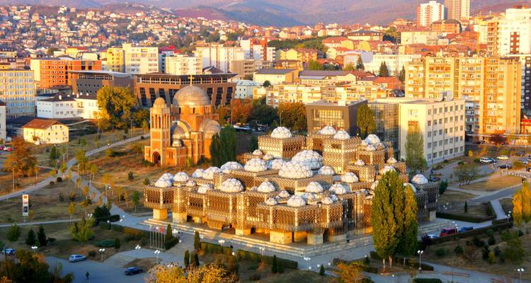 Aerial of Pristina showcasing the distinctive National Library and surrounding city skyline at sunset tones
