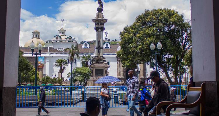 Vista a nivel de calle de la Plaza de la Independencia de Quito con la columna de la independencia enmarcada por arcadas
