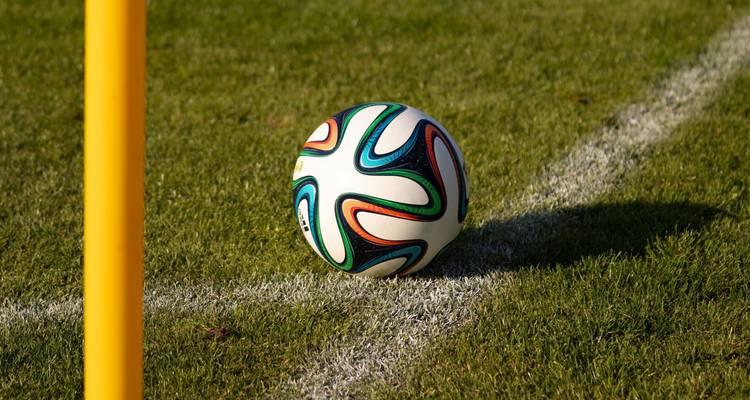 Close-up van een kleurige voetbal met patroon die bij de cornervlag op een grasveld staat