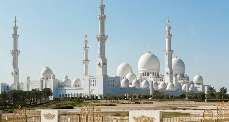Vista panorámica del complejo de la Gran Mezquita Sheikh Zayed con jardines bien cuidados bajo un cielo azul despejado.