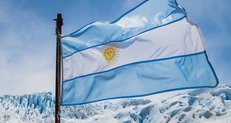 Argentinische Flagge, die mit vereisten Gletschergipfeln im Hintergrund weht.