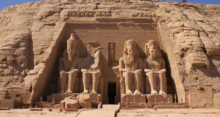 Les colosales statues assises sculptées dans la façade rocheuse du temple d'Abu Simbel sous une lumière diurne éclatante