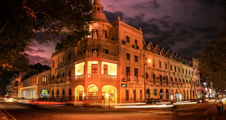 Verlicht koloniaal hotelgebouw in Kandy dat gloeit onder een dramatische schemering.