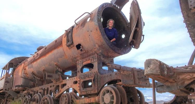 Reiziger zittend in de holle ketel van een verroeste stoomlocomotief op het Uyuni Treinen Kerkhof