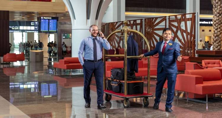 Deux hommes en costume dans un élégant hall d'hôtel à côté d'un chariot à bagages chargé de valises et d'une veste