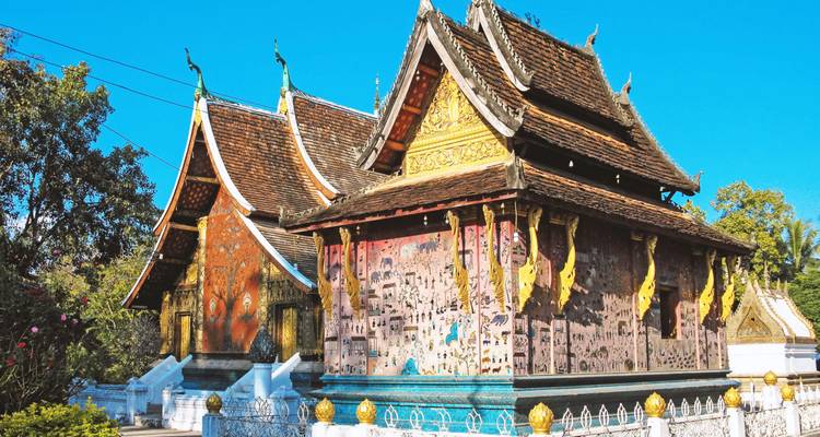 Rijkelijk versierde tempels van Wat Xieng Thong die schitteren onder een strakblauwe hemel.