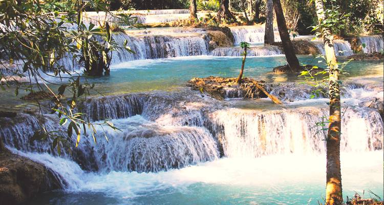 Turquoise trappen van Kuang Si watervallen die door groene jungle omlaag stormen.