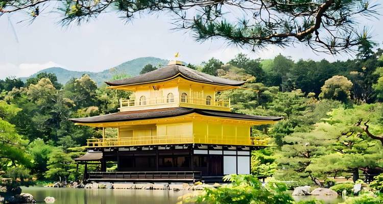 Goldener Pavillon Kinkaku-ji glänzend neben einem Spiegelbecken inmitten üppiger Grünflächen und Berge