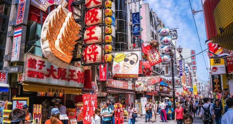 Belebte Dotonbori-Straße in Osaka gefüllt mit farbenfrohen Neonlichtern, riesiger Gyoza-Auslage und Menschenmengen