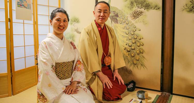 Man en vrouw in traditionele kledij zittend op tatami matten tijdens een theceremonie.