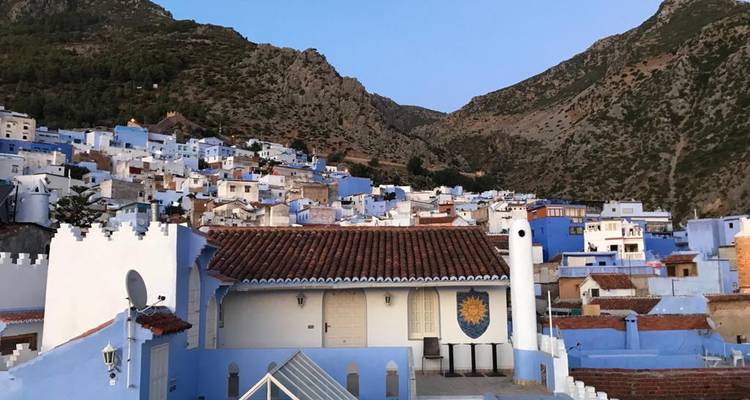 Pueblo pintado de azul en la ladera entre montañas al atardecer