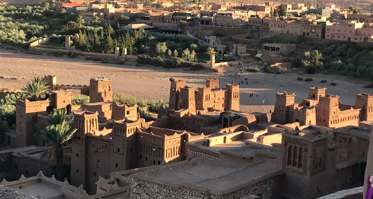 Complejo antiguo de kasbah de adobe a lo largo de un lecho de río seco bajo la cálida luz de la tarde