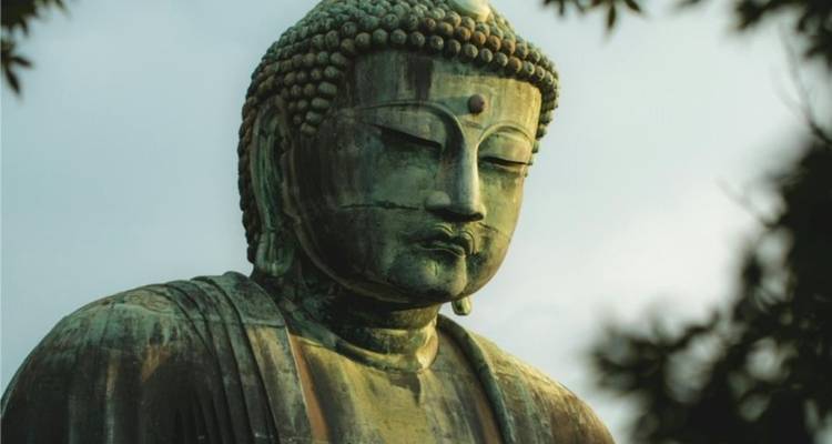 Close-up van het Great Buddha bronzen standbeeld in Kamakura omgeven door groen bladerdak.