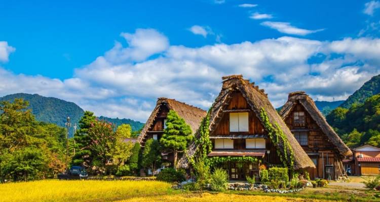 Casas de granja con techo de paja al estilo gassho tradicional en Shirakawago con montañas y cielos azules de fondo