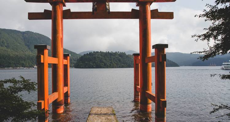 Vermillion-Torii-Tor stehend im Ashi-See mit nebligen bewaldeten Hügeln im Hintergrund