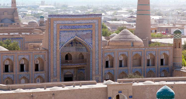 Ornate blue-tiled portal and brick domes of an ancient Silk Road madrasa seen from above