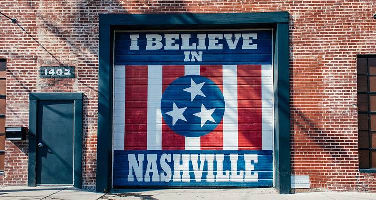 Une fresque murale en lettres grasses portant l'inscription « I Believe in Nashville » orne un mur en briques rouges dans une rue de la ville.
