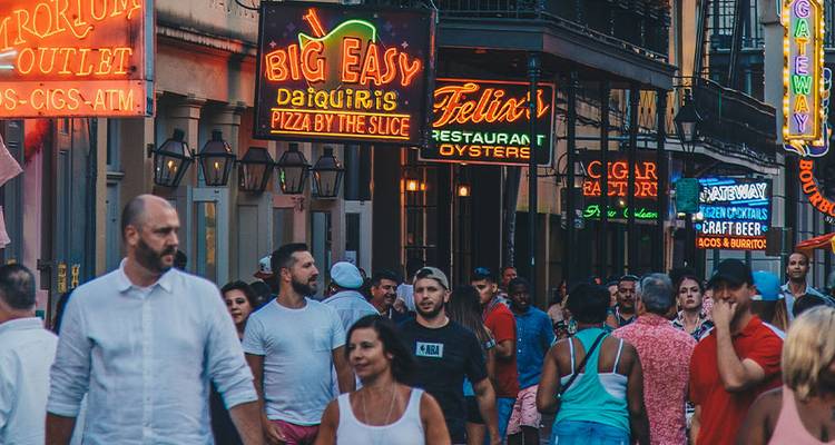 Les foules se promènent sous les enseignes de restaurants aux néons vibrants et les balcons du Quartier français.