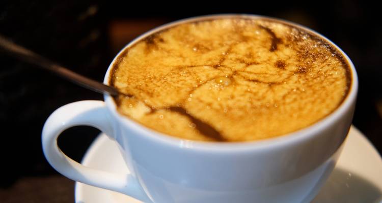 Gros plan d'un café vietnamien crémeux servi dans une tasse et une soucoupe blanches.