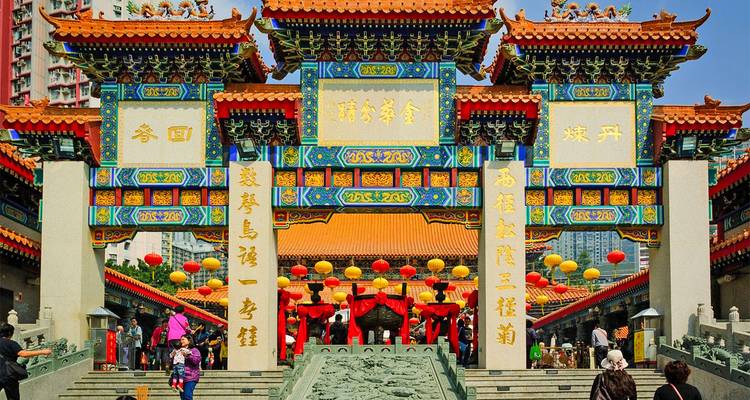 Farbenfrohe verzierte Eingangstore eines chinesischen Tempels, geschmückt mit Laternen und Besuchern darunter.