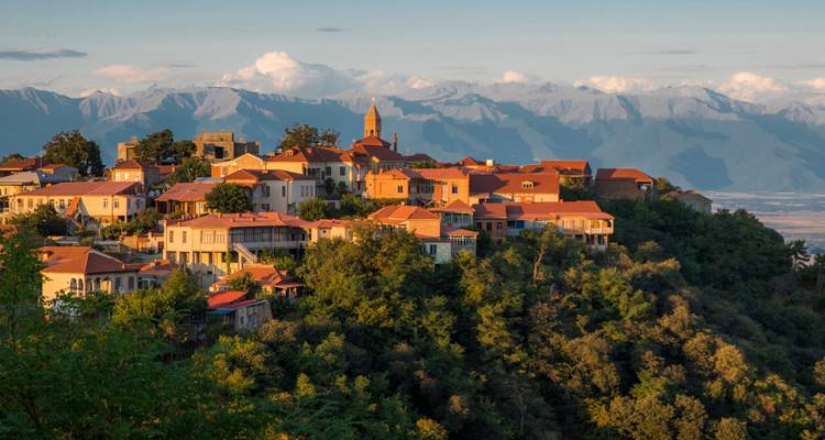 La ville de montagne de Sighnaghi aux toits en terre cuite au coucher du soleil avec les montagnes du Caucase en arrière-plan