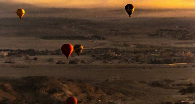 Vue granuleuse au crépuscule de ballons à air chaud lointains flottant au-dessus d'une ville désertique brumeuse.