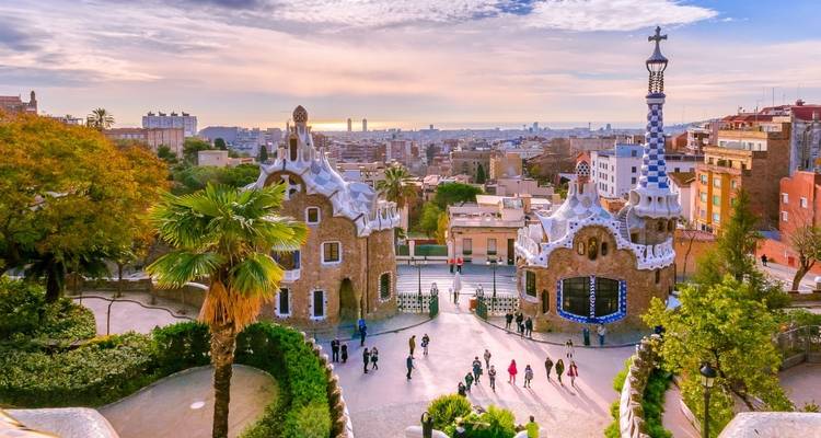 Vue panoramique des petites maisons en pain d'épices du parc Güell et de la ligne d'horizon de Barcelone à la lumière de l'aube.