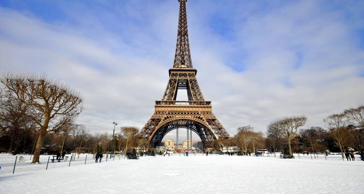 Schneebedeckter Champ de Mars, der zum Eiffelturm unter Winterhimmeln führt