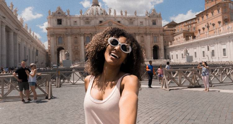 Femme prenant un selfie avec la Basilique Saint-Pierre en arrière-plan par une journée ensoleillée.