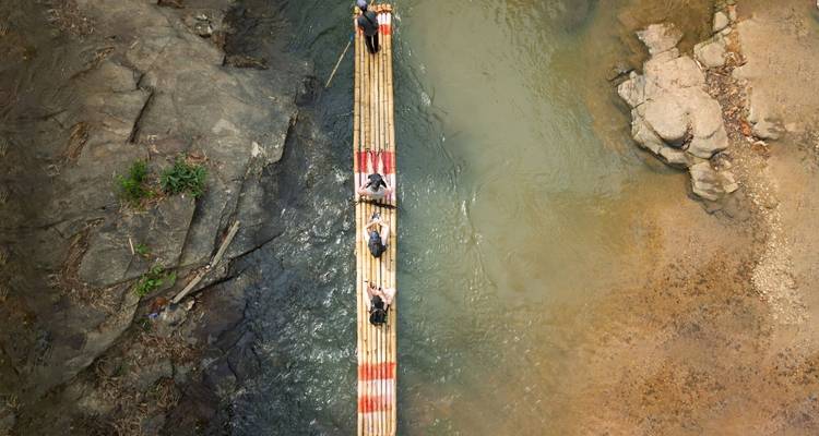 Vue aérienne de touristes naviguant sur un radeau en bambou étroit le long d'une rivière dans la jungle du nord de la Thaïlande.