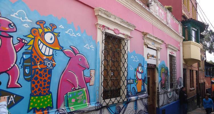 Los vibrantes murales de arte callejero decoran una fachada colonial rosa en el barrio La Candelaria de Bogotá.