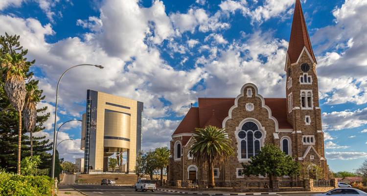 Historische Christuskirche naast het moderne Onafhankelijkheidsmonument in Windhoek onder dramatische wolken.