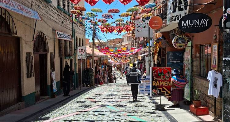 Une rue de fête ornée de parapluies et de drapeaux colorés descend en pente douce devant les magasins à La Paz.