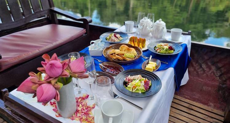 Elegant breakfast spread with tropical flowers and assorted dishes set on a boat table.