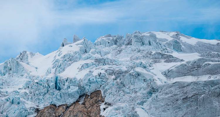 Vue rapprochée des formations de glace bleue dentelée sur un glacier sous un ciel dégagé.