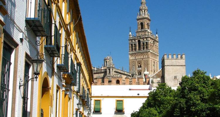 La tour des cloches de la Giralda s'élève au-dessus de bâtiments colorés et de balcons en fer à Séville.