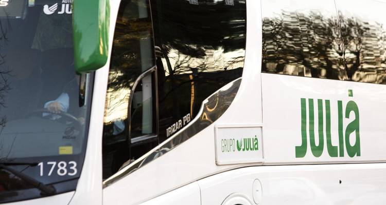 Détail du panneau latéral du car Julia avec le logo vert reflété dans les fenêtres.