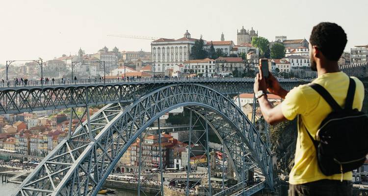 Un viajero fotografía el Puente Dom Luís I de Oporto y el paisaje urbano desde un punto de vista elevado.