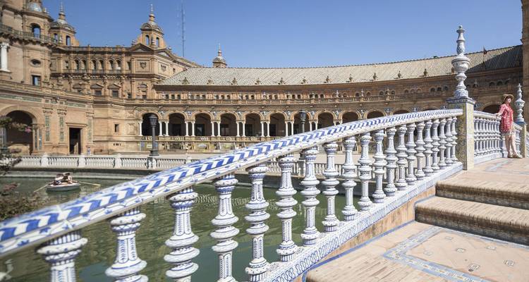 Ceramic bridged walkway and ornate balustrade at Plaza de España with visitors admiring the view.