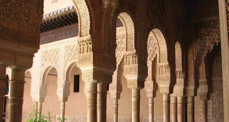 Detailed stucco arches and columns inside Granada's Alhambra palace complex.