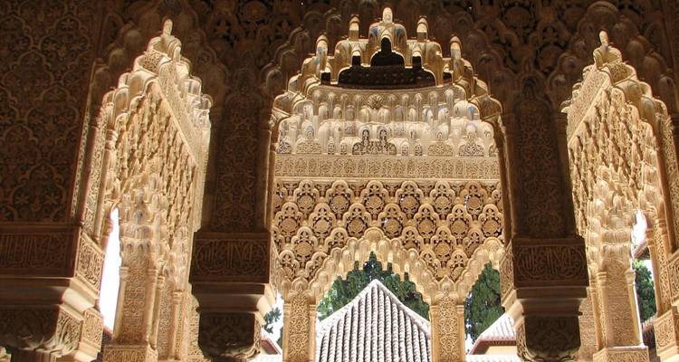 Intricately carved Moorish arches and muqarnas ceiling details inside the Alhambra.
