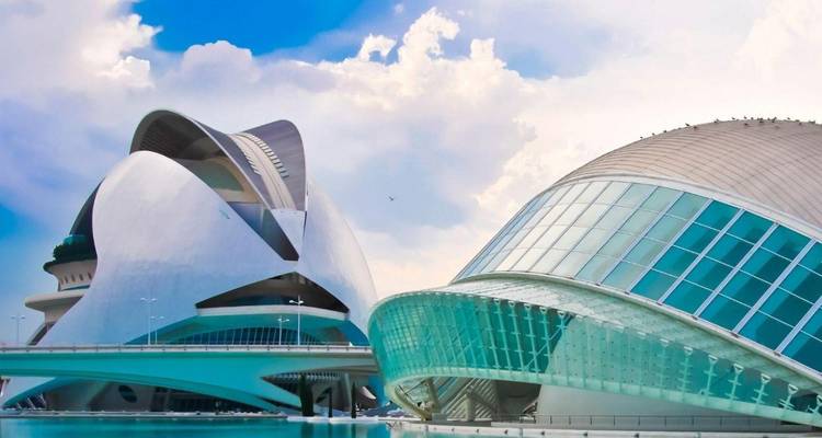 Edificios futuristas de cristal y blanco de la Ciudad de Artes y Ciencias de Valencia junto a una piscina azul.
