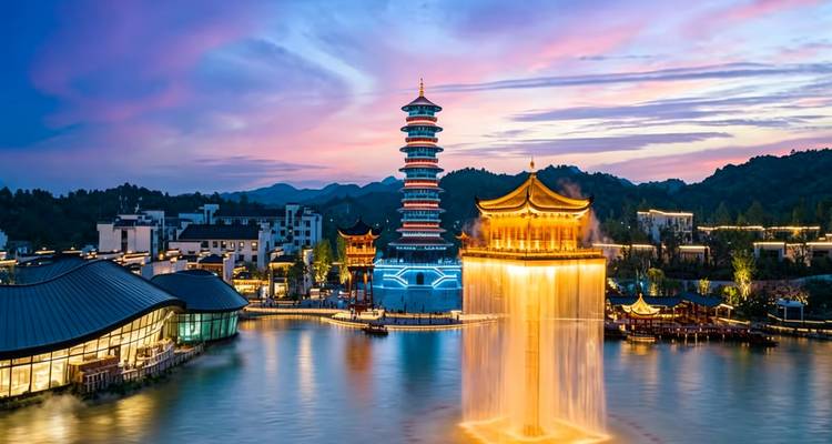 Atardecer colorido sobre un lago con una pagoda escalonada, un pabellón iluminado en azul y una fuente de agua espectacular.